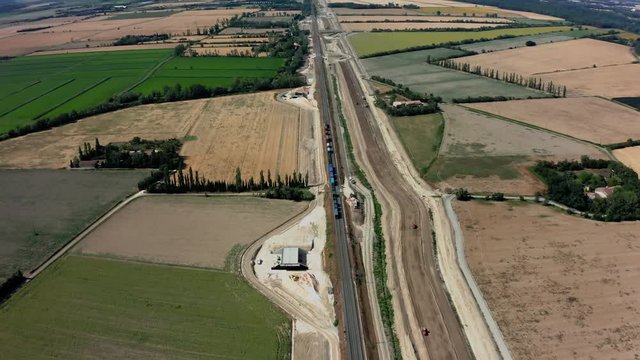 Aerial overhead of a train in France as it travels by construction site then into the distance
