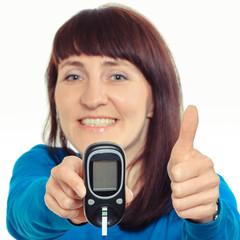 Smiling woman with glucose meter showing thumbs up. Checking sugar level