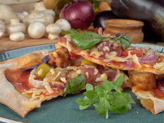 Pizza on thin dough.With slices of salami and ham ,olives and tomatoes. 