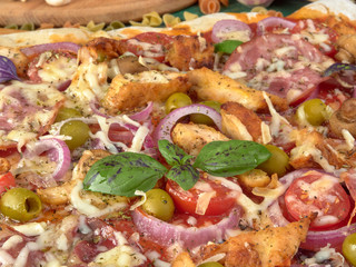 Pizza on thin dough.With slices of salami and ham ,olives and tomatoes. 