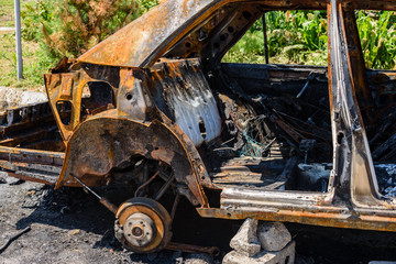 Burned car parked on the street, close-up. Abandoned burnt down car after an explosion, ready to be scrapped