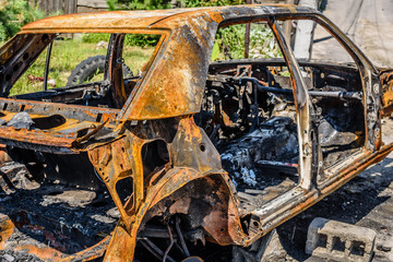 Burned car parked on the street, close-up. Abandoned burnt down car after an explosion, ready to be...