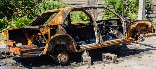 Burned car parked on the street, close-up. Abandoned burnt down car after an explosion, ready to be scrapped