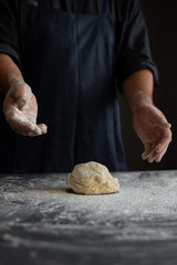 kitchen table, a piece of fresh raw dough, flour sprinkled, chef's male hands
