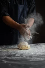 Poster chef in the kitchen, male hands knead the dough, clap hands, a cloud of flour © mtrlin
