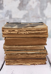 Stack of old ancient shabby books on a white wooden background.