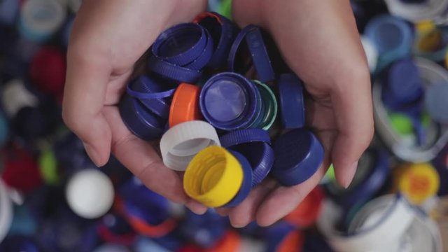 Hands cupping pile of plastic bottle caps and put them away
