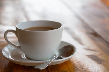 White cup of traditional indian tea masala with sauser and spon on wooden background. Close up.