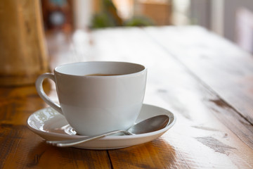 White cup of traditional indian tea masala with sauser and spon on wooden background.