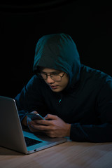 Hacker using a smartphone. Very dark nocturnal environment