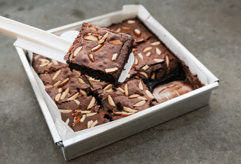Chocolate brownie squares with almond on aluminium tray, top view, horizontal composition. Flat lay food