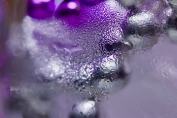 Abstract art texture of macro photographed ice through glass with condensation and colorful bokeh