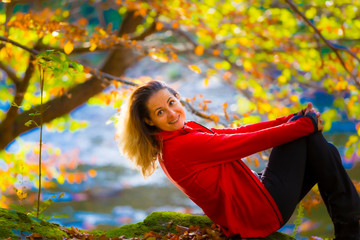 Beautiful happy young woman enjoying autumn on the bank of a wild mountain river