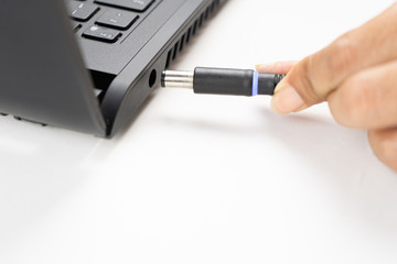 close up of battery charge on laptop computer with power plug
