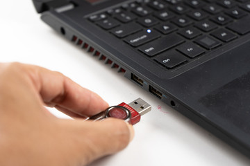 Close up of a woman hand connecting a pendrive in a laptop on a desktop