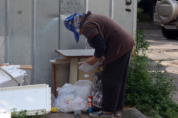 The elderly woman is looking for something useful in the trash . Ukrainian pension below the subsistence minimum.  Kiev,Ukraine