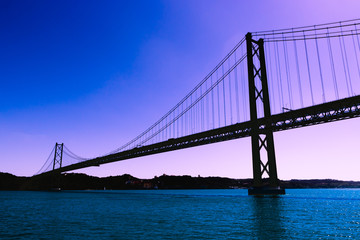 Fototapeta na wymiar Silhouette of large metal bridge across the sea Strait on the background of a fantastic purple sky
