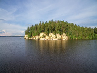 Stony coast with forest reflects in water of Kama river at the Khokhlovka. Perm region. Russia