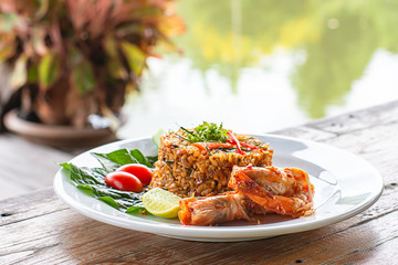 Fried rice with Shrimp on wooden table , spicy food Thai style Background rivers and trees.