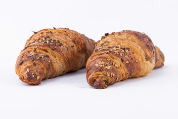 Closeup of two croissants sprinkled with powdered sugar and sesame seeds