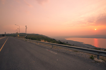 Fototapeta premium panoramic natural background of the evening's natural scenery (mountains, rivers, grasslands, roads, sunshine from the sun) is blurred through the cool, often seen in scenic spots or attractions while