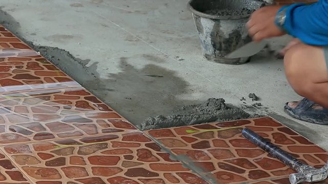Technicians are laying tiles on the floor with cement.