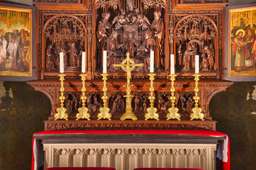 Catholic altar with tryptich, devotional candles and a cross.