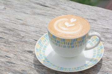 Hot coffee (cappuccino, latte) with milk in ceramic white cup on wooden table. Copy space for your...