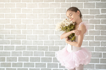 Cute little young preschool girl ballerina dance in pink leotard and tutu holding flowers bouquet...