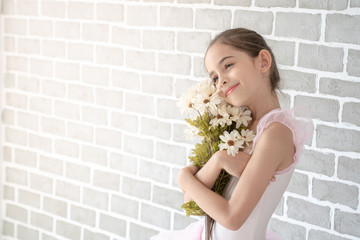 Cute little young preschool girl ballerina dance in pink leotard and tutu holding flowers bouquet...