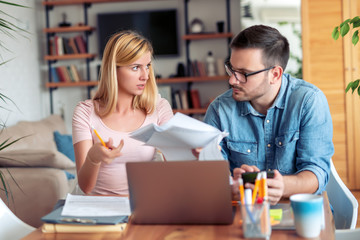 Worried young couple checking bills