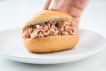 Frau isst Nordseekrabben Brötchen als Fischbrötchen als schneller regionaler Imbiss