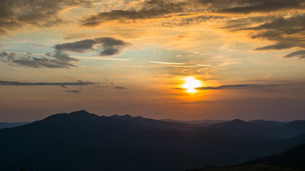 Stunning sunset in the mountains. Orange sky and mountains silhouettes. Carpathian Mountains. Bieszczady. Poland