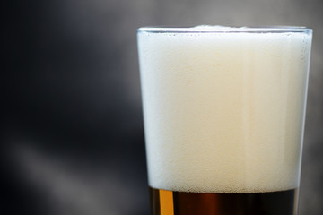 Glass of light beer close-up on a dark background