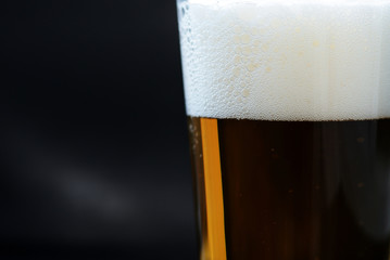 Glass of light beer close-up on a dark background