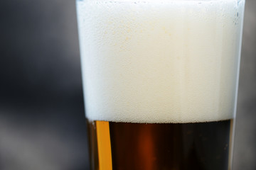 Glass of light beer close-up on a dark background