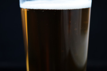 Glass of light beer close-up on a dark background