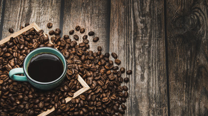 cup of coffee and beans on brown wooden table with text space