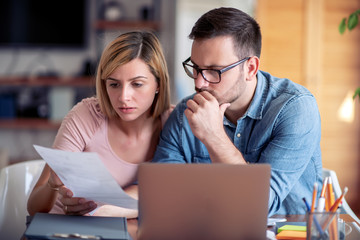 Worried young couple checking bills
