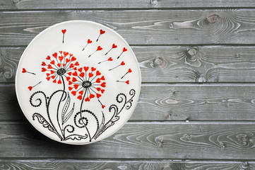 Decorative ceramic plates hand painted dot pattern with acrylic paints on a gray wooden background. Copy space.