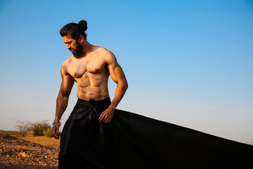 Young handsome long hair and beard Asian muscled fit male model man posing outdoor against blue sky...