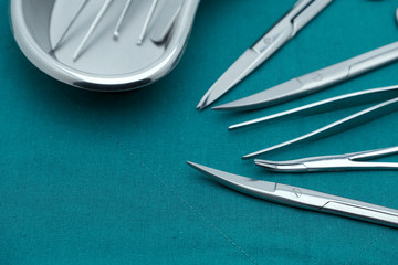 Basic surgical instrument forceps tweezers scissors in emesis or plus basin on surgical green drape...