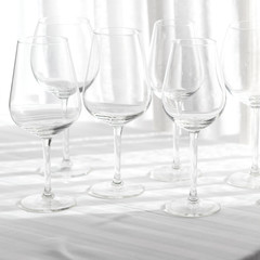 Several empty wine glasses in white grey shades on the white tablecloth for abstract background