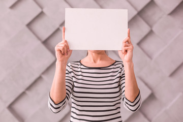 Woman covering her face with a blank poster