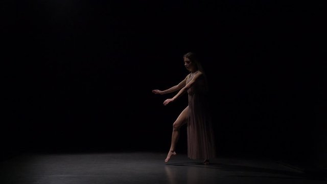 Slow motion of sporty maiden dancing contemp in dark studio.