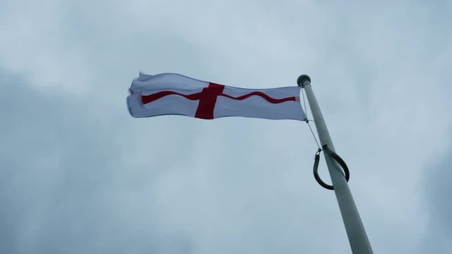 English flag against an overcast sky on a windy day, filmed in Slow motion.