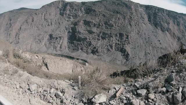 Car moves on the narrow, gravel, bumpy road in mountains and climbs the hill