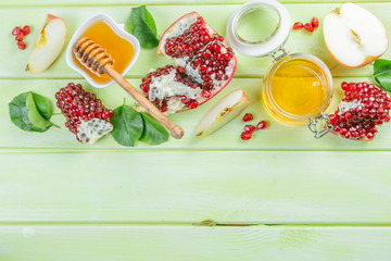 Rosh hashana jewish holiday concept - apples, honey, pomegranate, green wood background