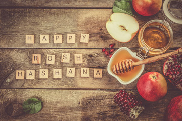 Rosh hashana jewish holiday concept - apples, honey, pomegranate, rustic wood background