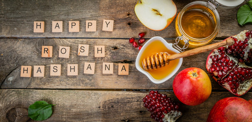 Rosh hashana jewish holiday concept - apples, honey, pomegranate, rustic wood background
